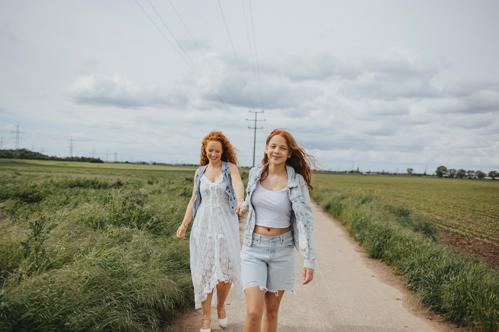 Bewegte Aufnahme Portraitshooting mit Mama und Tochter in Ladenburg zwischen zwei Feldern. Rote Haare und Sommersprossen. Echte Emotionen Hand in Hand