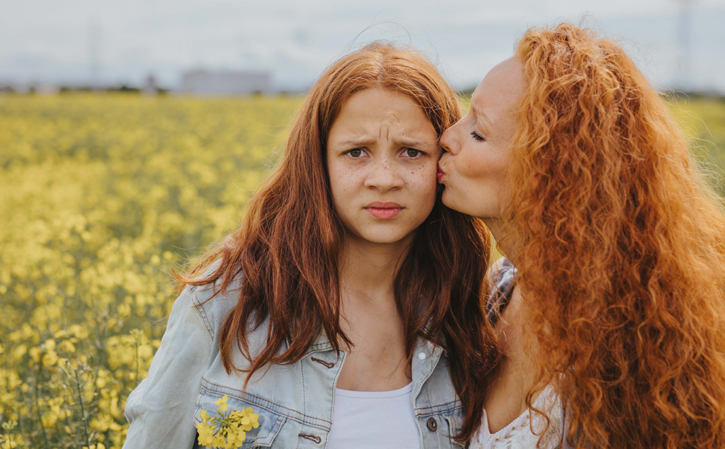 Mama knutscht ihre Tochter. Kritischer Blick. Rote Haare und Sommersprossen. Fotoshooting Rapsfeld Ladenburg