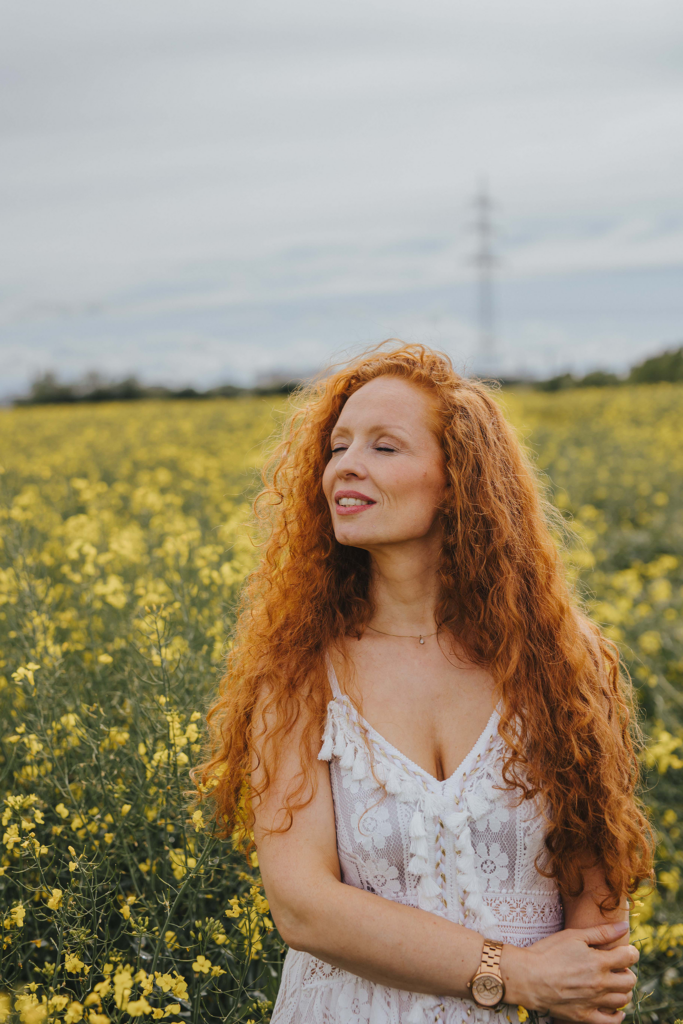 Träumen im Rapsfeld bei Ladenburg. Frau mit roten Haaren. Portraitbild mit weißem Boho Kleid