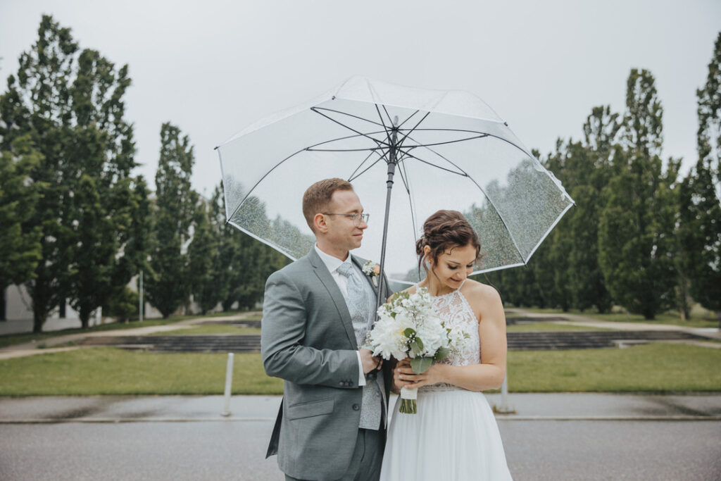Brautpaar unter durchsichtigem Regenschirm. Mitten in einer Allee in Ostfildern.